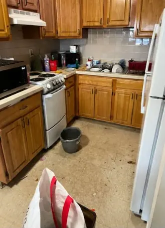 Kitchen before cleaning with dishes on counters and a mop bucket on the floor