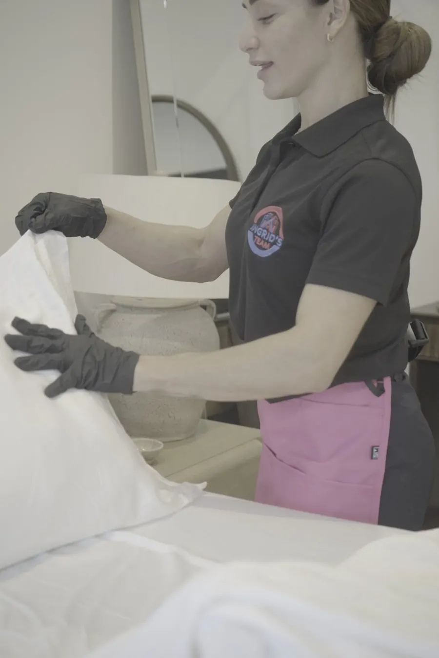 Ingrid's Team cleaner making a bed with fresh white linens